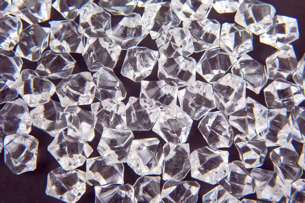 Parlak kristaller karanlık bir yüzeye dağılmış, ışığı güzel yansıtıyor, lüks ve zarafet temalı tasarımlar veya şenlikli dekorasyonlar için mükemmel..