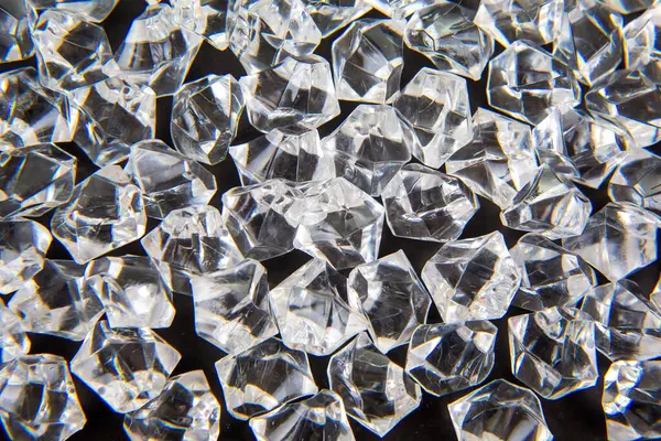 Parlak kristaller karanlık bir yüzeye dağılmış, ışığı güzel yansıtıyor, lüks ve zarafet temalı tasarımlar veya şenlikli dekorasyonlar için mükemmel..