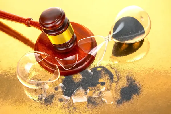 Altın bantlı geleneksel bir tokmak, siyah kumlu kırık bir kum saatinin yanında oturur, lüks altın bir arka plana karşı, adaleti ve zamanın geçişini hatırlatır..