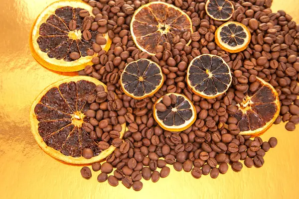 Sıcak tonlu kahve çekirdekleri ve portakal dilimleri yansıtıcı altın bir zemin üzerinde, yiyecek ve içecek fotoğrafçılığı için ideal. Kahve aroması ve turunçgiller.