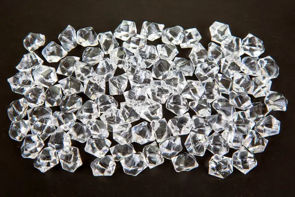 Karanlık bir yüzeyde şeffaf kristaller parıldıyor, göz kamaştırıcı bir efektle ışığı yansıtıyor, şenlikli, lüks veya takıdan esinlenilmiş bir sahne yaratmak için ideal..