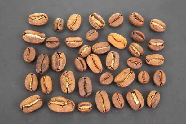 Yüksek çözünürlüklü kahve çekirdekleri, zengin tonlarda ve koyu dokulu arka planda bölünmüş yüzeyler. Kahve kültürü ve içecek imgeleri için ideal..