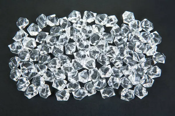 Karanlık bir yüzeyde şeffaf kristaller parıldıyor, göz kamaştırıcı bir efektle ışığı yansıtıyor, şenlikli, lüks veya takıdan esinlenilmiş bir sahne yaratmak için ideal..