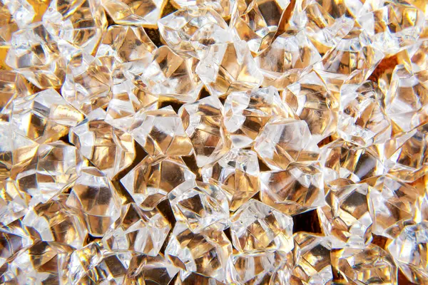 Parlak kristaller altın bir yüzeye saçılmış, ışığı güzel yansıtıyor, lüks ve zarafet temalı tasarımlar veya şenlikli dekorasyonlar için mükemmel..