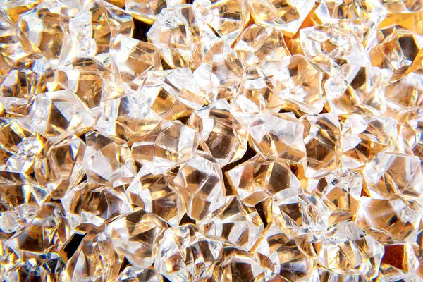 Parlak kristaller altın bir yüzeye saçılmış, ışığı güzel yansıtıyor, lüks ve zarafet temalı tasarımlar veya şenlikli dekorasyonlar için mükemmel..