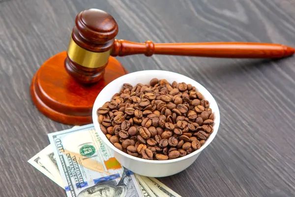 Tahta bir yüzey üzerinde kahve kabının içindeki kahve çekirdekleri ile birlikte, yasal masrafları ve kahve ticareti endüstrisini temsil eden bir tokmak..