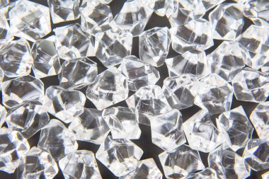 Parlak kristaller karanlık bir yüzeye dağılmış, ışığı güzel yansıtıyor, lüks ve zarafet temalı tasarımlar veya şenlikli dekorasyonlar için mükemmel..