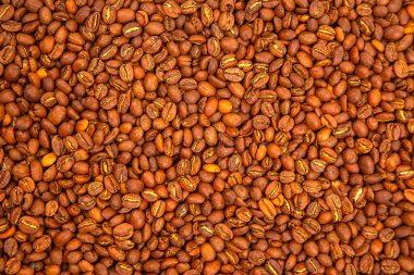 Kavrulmuş kahve çekirdekleri, koyu kahverengi renklerini sergiliyor ve yoğun bir düzende çatlak yüzeyler oluşturuyor. Gurme yemek ve içecek fotoğrafçılığı için ideal..