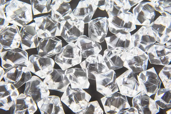 Parlak kristaller karanlık bir yüzeye dağılmış, ışığı güzel yansıtıyor, lüks ve zarafet temalı tasarımlar veya şenlikli dekorasyonlar için mükemmel..