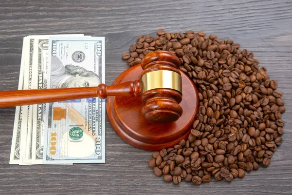 100 dolarlık banknot, kahve çekirdekleri ve ahşap bir masanın üzerindeki tokmak iş ve ticaret anlaşmazlıklarını resmetmek için ideal olan finans, hukuk ve kahve piyasası temalarını çağrıştırıyor.