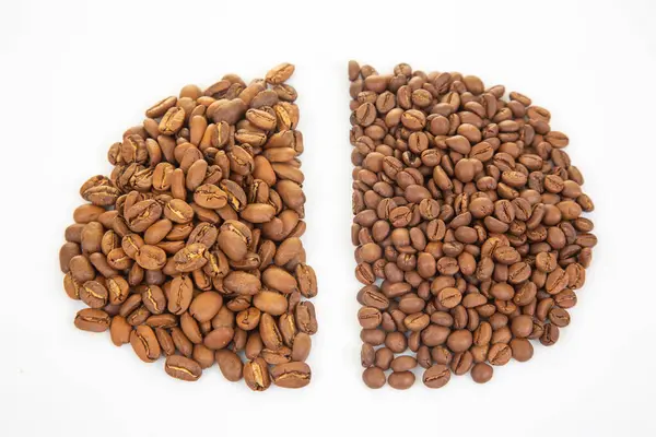 Yüksek çözünürlüklü kahve çekirdekleri beyaz arka planda çeşitli kahverengi gölgelerle eşsiz dokularını ve yarıklarını gösteriyor. Kahve kültürü için uygun..