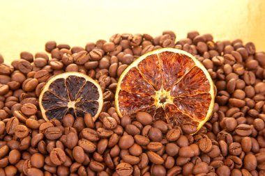 Kavrulmuş kahve çekirdeklerinin arasına yerleştirilmiş canlı bir portakal dilimleri sıcak, aromatik aromatik narenciye ve kahve dokuları oluşturur. kahve aroması ve tat tanımlayıcıları