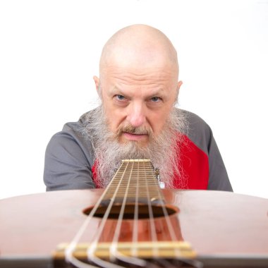 Yaşlı kel adam, gri sakallı, akustik gitarlı, gri spor gömlekli, beyaz arka planda soyutlanmış, tutkulu bir müzik ifadesini vurgulayan biri..
