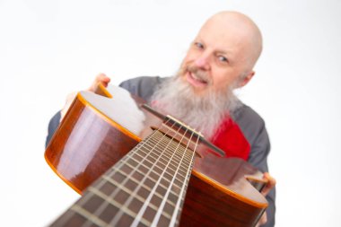 Yaşlı kel adam, gri sakallı, akustik gitarlı, gri spor gömlekli, beyaz arka planda soyutlanmış, tutkulu bir müzik ifadesini vurgulayan biri..