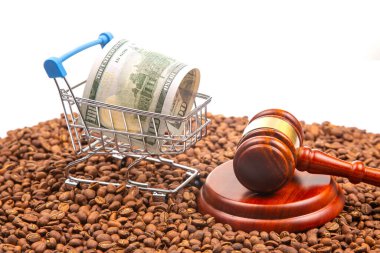 Kahve çekirdekleri, elinde 100 dolarlık banknot ve bir tokmak olan bir alışveriş arabasının arka planında yasal ticaret ve mali adalet temaları resmedilmiş.
