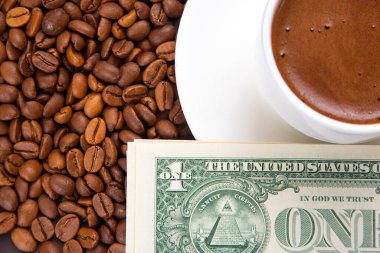 Kahveye finansal yatırım. Kavrulmuş kahve çekirdekleri ve dolarlarla çevrili bir fincan sıcak espresso.