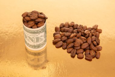 Parlak altın bir yüzey üzerinde kahve çekirdekleri ile dolup taşan bir dolarlık banknotları yuvarladı. Etrafa saçılmış daha fazla fasulye zenginlik ve ticareti temsil ediyordu.