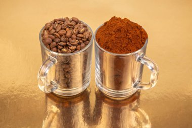 Altın bir zemin üzerinde iki cam bardak yakın plan, biri tamamen kavrulmuş kahve çekirdekleri ile dolu, diğeri ise zengin kahve çekirdekleri ile. Mutfak ya da içecek kavramları için ideal