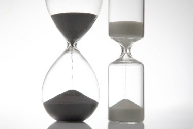 Sade beyaz bir zemin üzerinde akan koyu kumlu parlak bir kum saati zamanı sembolize ediyor. Asgari, zamana bağlı temalar için ideal