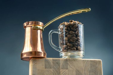 Parlak bakır bir Türk kahve makinesinin yakın çekimi ve ahşap bir bloğa konmuş kahve çekirdekleri taşan şeffaf bir fincan. Sıcak tonlu, zengin, aromatik bir kahve konsepti..