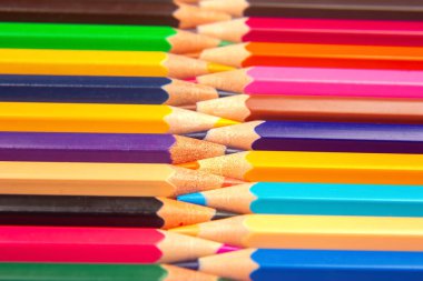 Beyaz bir yüzeye karşı istiflenmiş ızgara desenli renkli kalemler. Sanat, eğitim ve tasarım temaları için parlak ve dinamik bir görsel cazibeye sahip ideal.