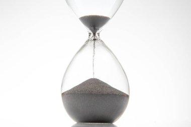 Beyaz zemine siyah kum damlayan minimalist kum saati. Zaman yönetimi, teslim tarihleri ya da basitlik kavramları için mükemmel..