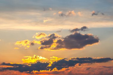 Gün batımında güzel bir gökyüzü serpilmiş bulutlardan yansıyan altın sarısı renkler. Yumuşak pastel renkler ve koyu gölgelerin karışımı huzurlu ve rüya gibi bir manzara yaratır..