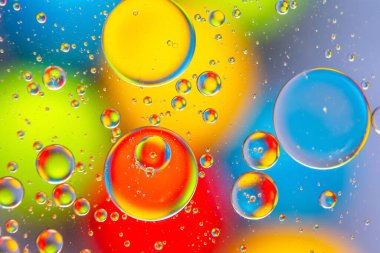 Parlak bir yüzeyde kırmızı, sarı, mavi ve yeşil renkli parlak su damlacıkları, soyut sanat veya tasarım için mükemmel..