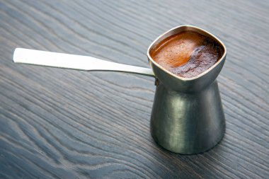 Koyu ahşap bir masanın üzerinde kremalı Türk kahvesi olan geleneksel bir kahve. Kahve tutkunları, kültürel çalışmalar ya da gurme yemek görselleri için uygundur..