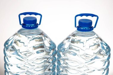 Mavi kapaklı iki plastik su şişesi ve beyaz arka planda izole edilmiş eşsiz dalgalı bir tasarım. Sağlık, hidrasyon veya ekolojik bilinçli ürün hisse senedi tasviri için uygundur..