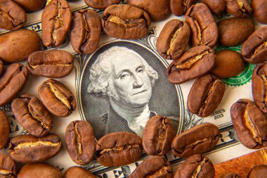 Kavrulmuş kahve çekirdekleri, ortada George Washington 'ın portresi olan bir Amerikan doları banknotuna saçılmış. Kahve ticareti, ekonomi, finans ve kafein bağımlılığını sembolize eder