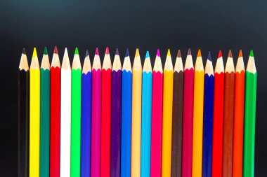 Dinamik dalga biçiminde renkli kalemler, kırmızı, mavi, sarı ve daha fazlası, minimalist gri arka planda yer almaktadır. Sanat, eğitim ve yaratıcılık konuları için ideal.