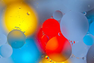 Parlak bir yüzeyde kırmızı, sarı, mavi ve yeşil renkli su damlacıkları, yeni bir görünüme sahip soyut ve yaratıcı bir arka plan sunuyor..