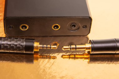 Yansıtıcı altın bir yüzey üzerinde altın konnektörlü 3.5 mm 'lik iki ses kriptosu, teknoloji ve ses ekipmanları teması için ideal