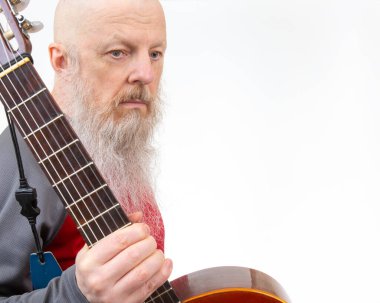 Yaşlı kel adam, gri sakallı, akustik gitarlı, gri spor gömlekli, beyaz arka planda soyutlanmış, tutkulu bir müzik ifadesini vurgulayan biri..
