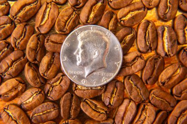 Kavrulmuş kahve çekirdekleri ve altın bir zemin üzerine on sentlik ölçeklendirilmiş kahve çekirdekleri, sıcak kahverengi gölgelerini ve detaylı dokularını vurguluyor. Kahve kültürü ve ölçek tasvirleri için harika..