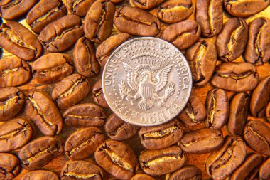 Kavrulmuş kahve çekirdekleri ve altın bir zemin üzerine on sentlik ölçeklendirilmiş kahve çekirdekleri, sıcak kahverengi gölgelerini ve detaylı dokularını vurguluyor. Kahve kültürü ve ölçek tasvirleri için harika..