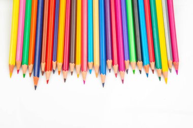 Beyaz arka planda çeşitli renklerde keskin renkli kalemlerle dolu canlı bir sıra. Sanat malzemeleri, yaratıcılık ve okula dönüş temaları için mükemmel..