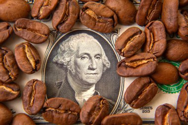 Kavrulmuş kahve çekirdekleri, ortada George Washington 'ın portresi olan bir Amerikan doları banknotuna saçılmış. Kahve ticareti, ekonomi, finans ve kafein bağımlılığını sembolize eder