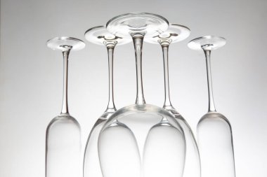 Farklı tasarımları olan beş boş şarap kadehinden oluşan şık bir koleksiyon, yansımaları parlak bir yüzey üzerinde ayna etkisi yaratıyor, şarap tatma temaları için harika..