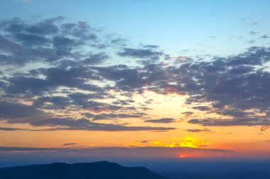 Gün batımında güzel bir gökyüzü serpilmiş bulutlardan yansıyan altın sarısı renkler. Yumuşak pastel renkler ve koyu gölgelerin karışımı huzurlu ve rüya gibi bir manzara yaratır..