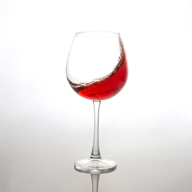 Havada kaydedilen kırmızı şarabın çarpıcı bir yansıması, berrak bir şarap bardağının içinde, yumuşak beyaz bir zemin üzerinde dönüyor. İçki reklamları, şarap kültürü ya da dinamik içki fotoğrafçılığı için mükemmel.