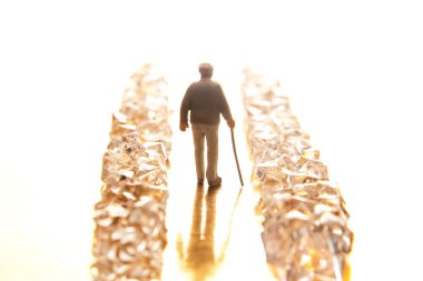 Minik takım elbiseli bir şahıs parlak kristal bir yolda yürür altın bir zeminde, başarının ve lüksün peşinde koşmanın somutlaştırıcısıdır..