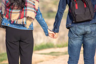 Bir çift, yeşilliklerle çevrili manzaralı bir yolda el ele yürür. Güneş ışığı günlük kıyafetlerini ön plana çıkarıyor. Güzel bir günde romantik bir atmosfer yaratıyor..