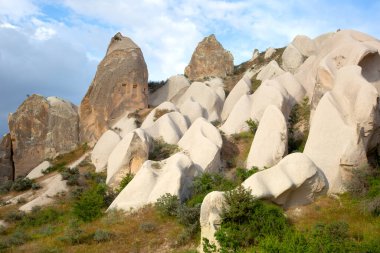 Kapadokya 'nın büyüleyici kaya oluşumlarını keşfedin. Parlak gökyüzü altındaki yemyeşil jeolojik yapılar, Türkiye' nin doğal güzelliğini ve cazibesini yakalar..