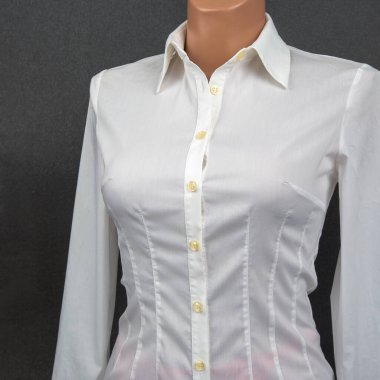 Kadınlar için özel diktirilmiş uzun kollu bir gömlek siyah bir arka plana karşı bir mankende sergileniyor..