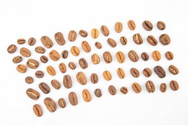 Farklı kahve çekirdekleri beyaz bir yüzeye yayılarak belirgin şekillerini ve renklerini gösterirler. Düzenleme, dokulardaki çeşitliliği ve kızartma seviyelerini vurgular.