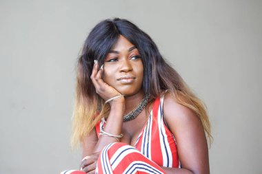 Afrikalı bir kadın nazikçe oturur, çenesini elinin üstüne koyar ve derin düşüncelere dalardı. Kalın çizgili şık bir elbise giyiyor. Etrafı modern ışıkla çevrili..