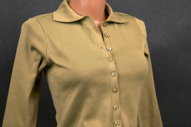 Uzun kollu bej bir üst, koyu bir arka planda sergilenen şık bir tasma ve parlak düğmeler içerir. Kumaşın pürüzsüz bir dokusu var. Elbisenin zarifliğini arttırıyor..