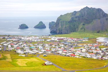 Renkli evler ve yemyeşil tarlalarla İzlanda kıyısında büyüleyici bir köy bulunuyor. Görkemli kayalık kayalıklar okyanustan dramatik bir şekilde yükselir ve çarpıcı bir doğal zemin yaratır..